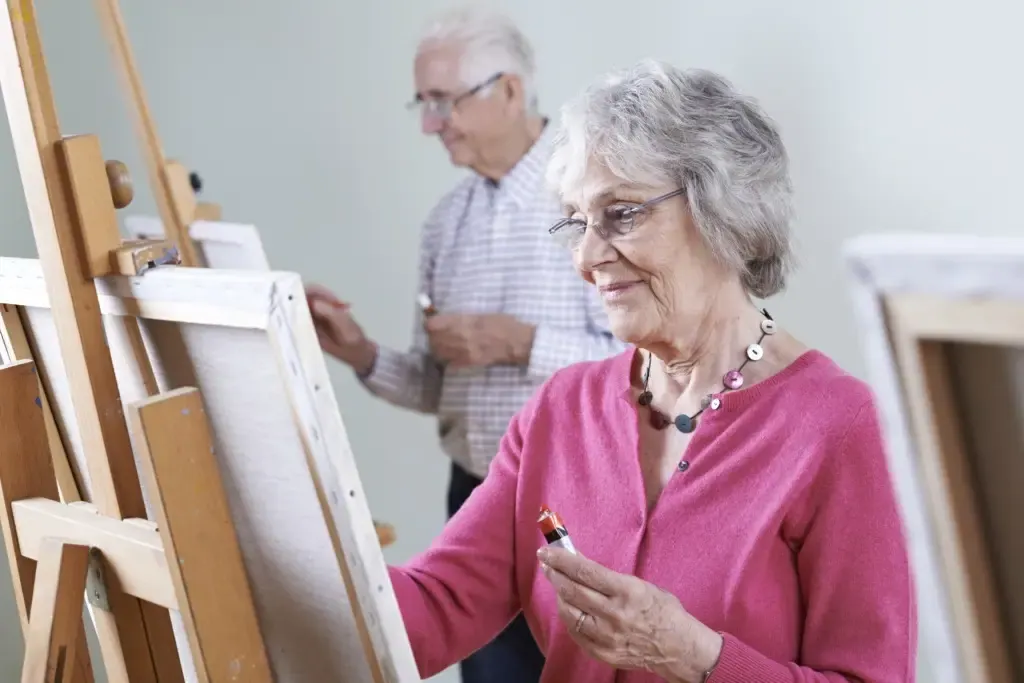 A resident of The Maple Village painting at an easel during an art program