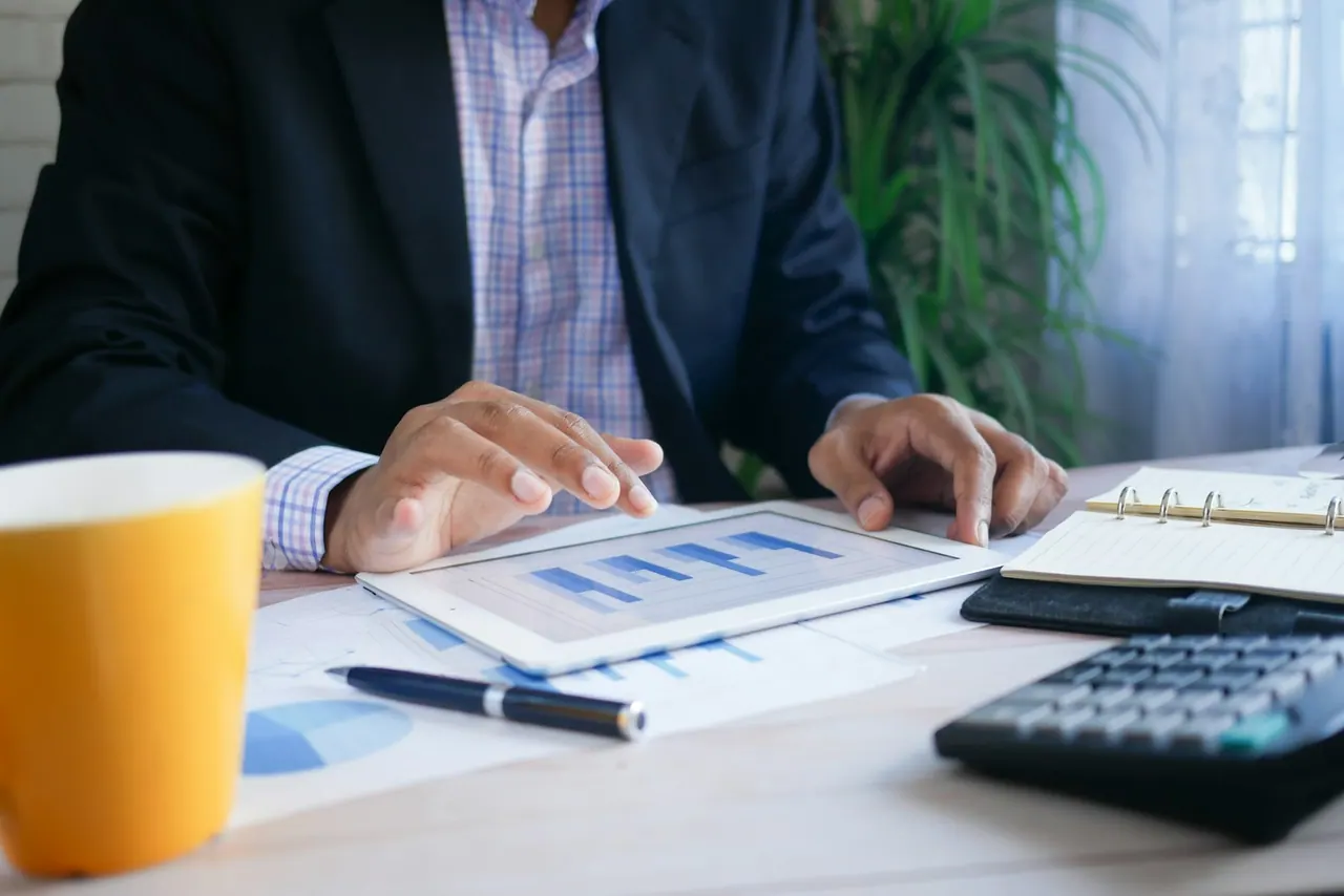 An accountant going through charts on a tablet at his desk