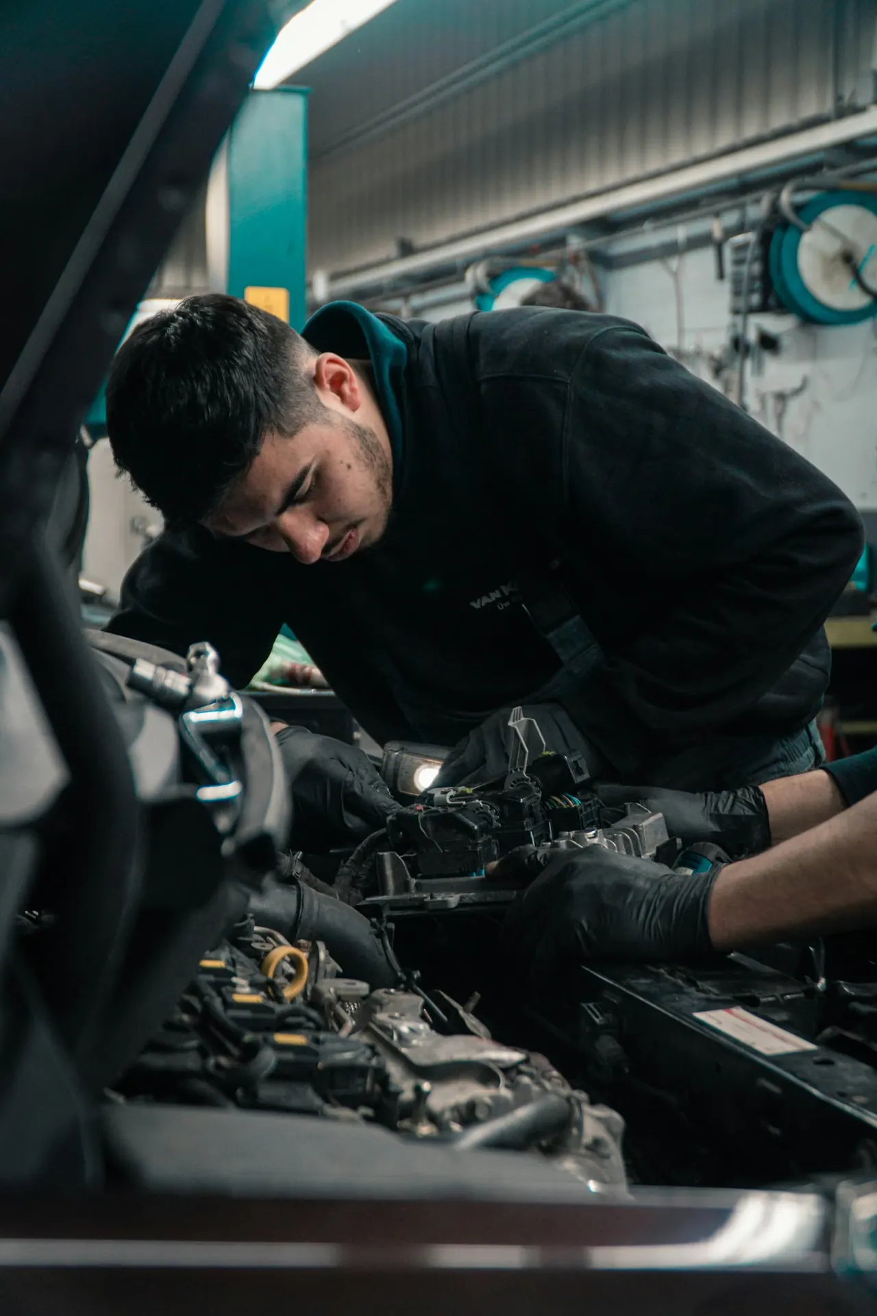 A mechanic in gloves working on an engine