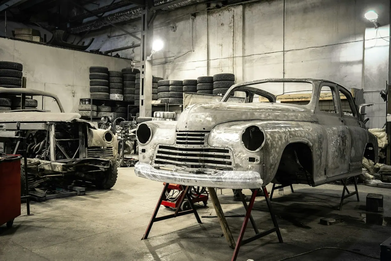 An older car stripped to bare metal on stands in a quiet restoration bay