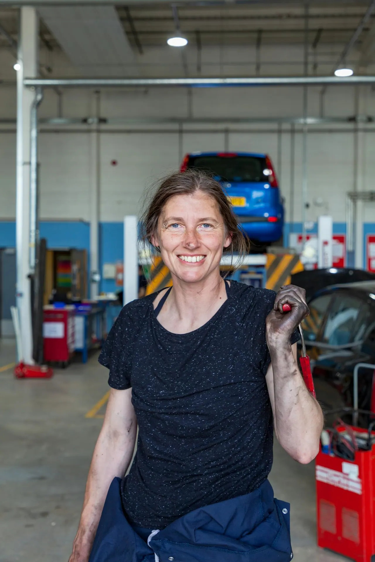 A smiling technician holding a wrench in a bright workshop