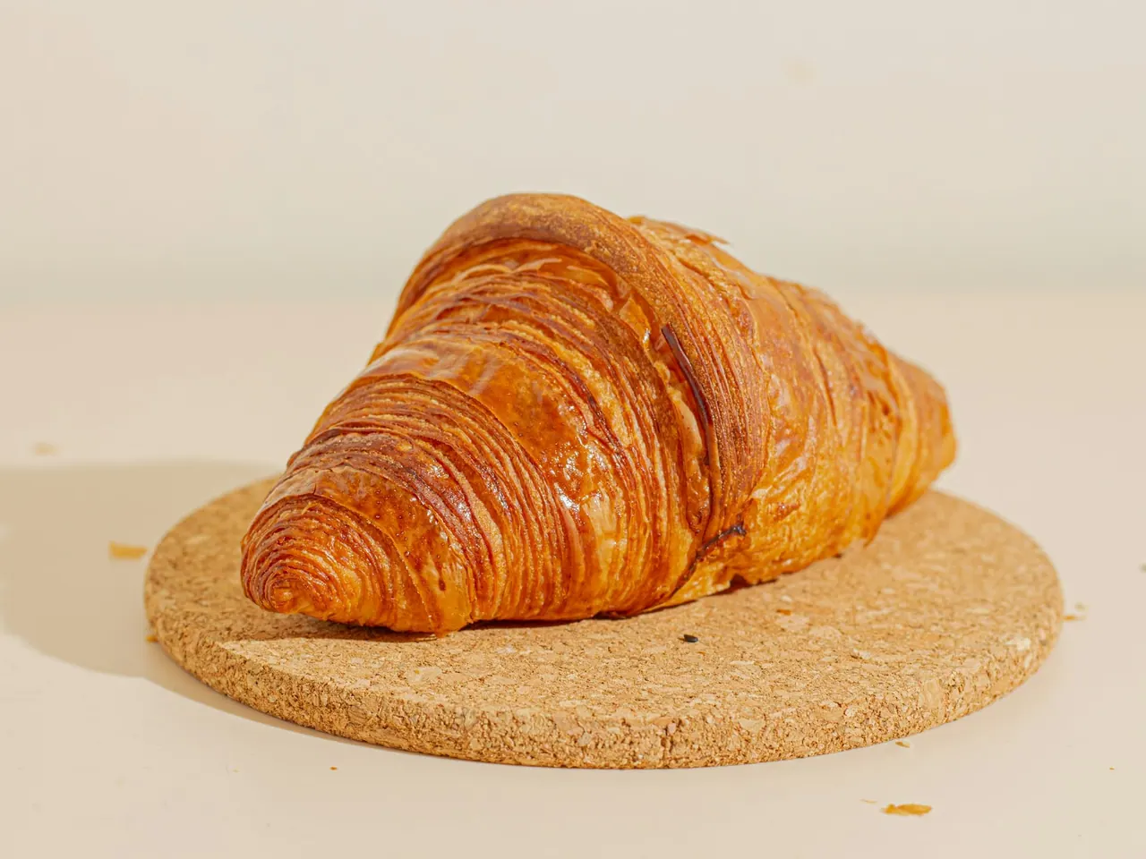 A golden croissant on a cork coaster