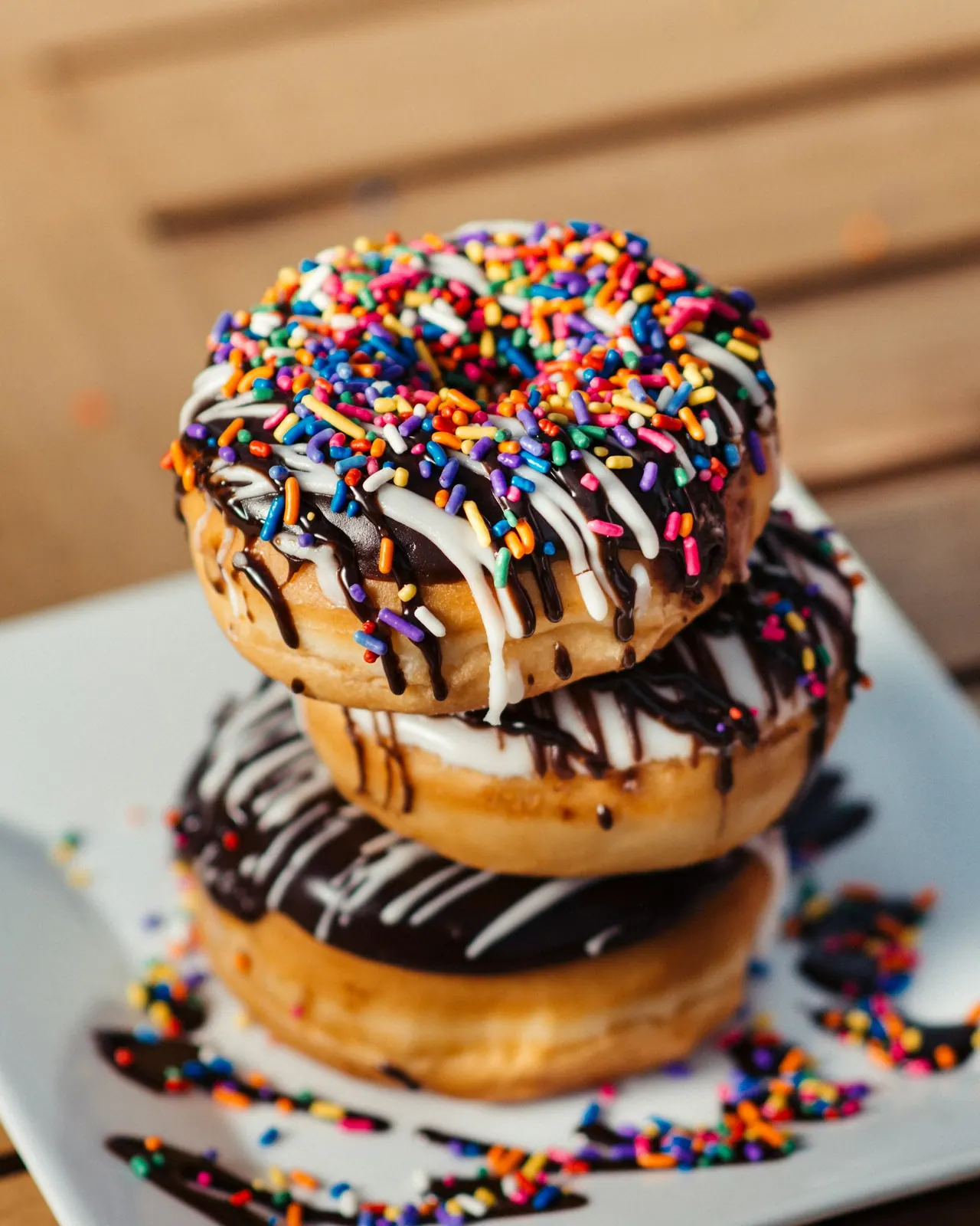 A stack of chocolate doughnuts with rainbow sprinkles