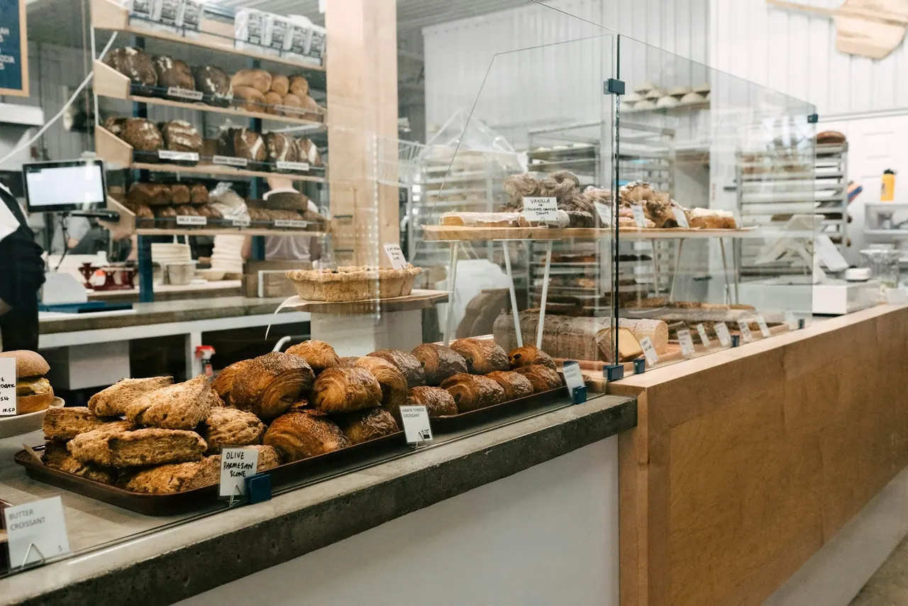A bright bakery counter lined with fresh loaves and pastries
