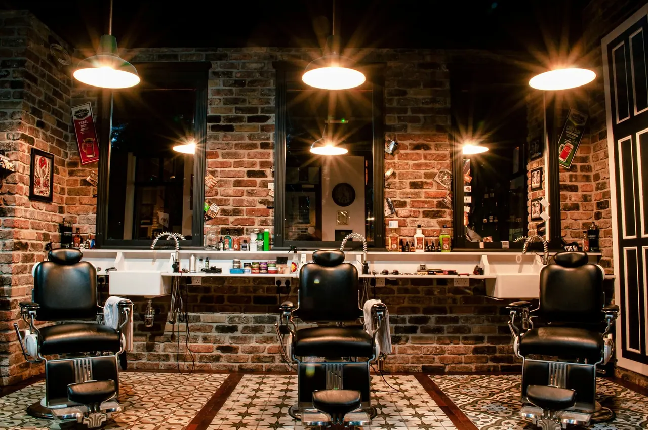 Leather barber chairs under warm lights against an exposed brick wall