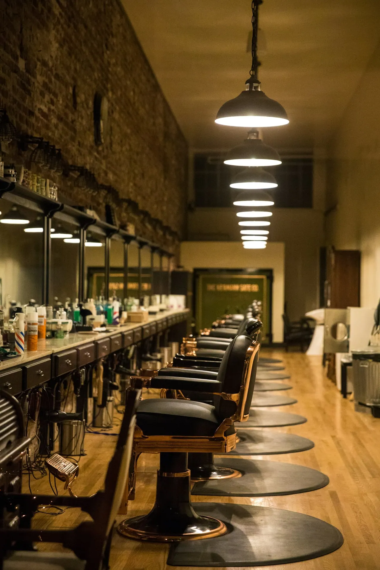 The shop’s long row of barber chairs under pendant lamps
