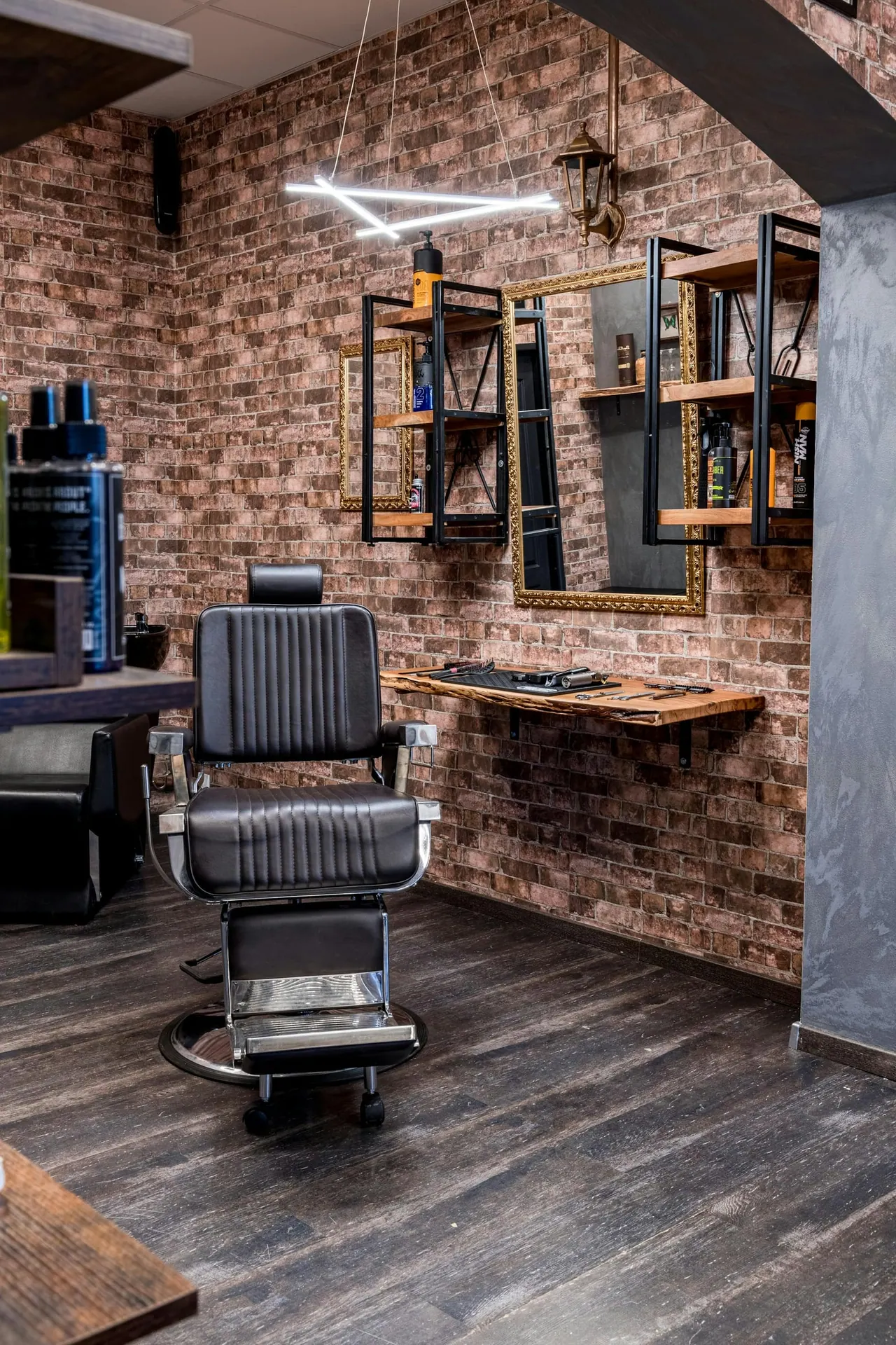 A barber chair by a brick wall with shelves and mirrors