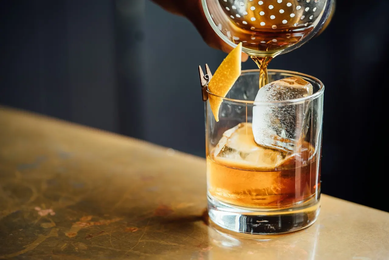 Whisky poured over a clear ice ball on the bar