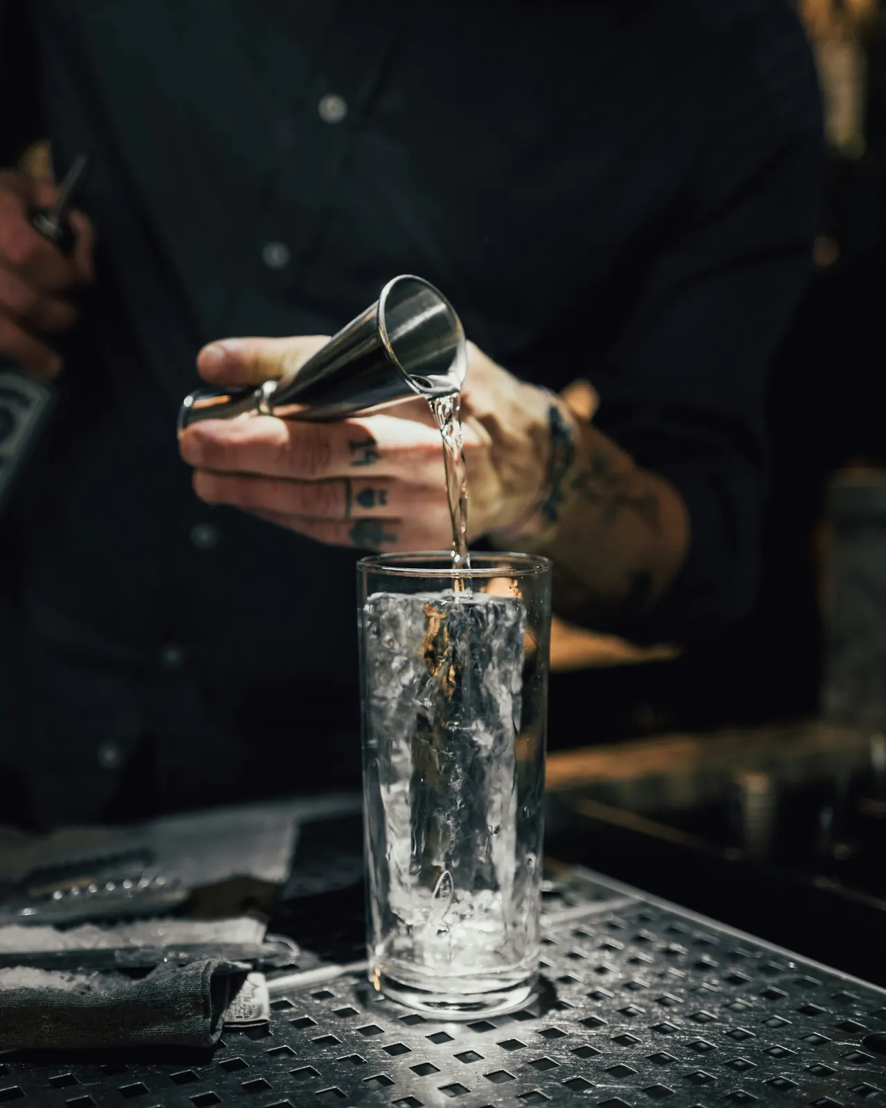 A bartender measuring a pour with a jigger