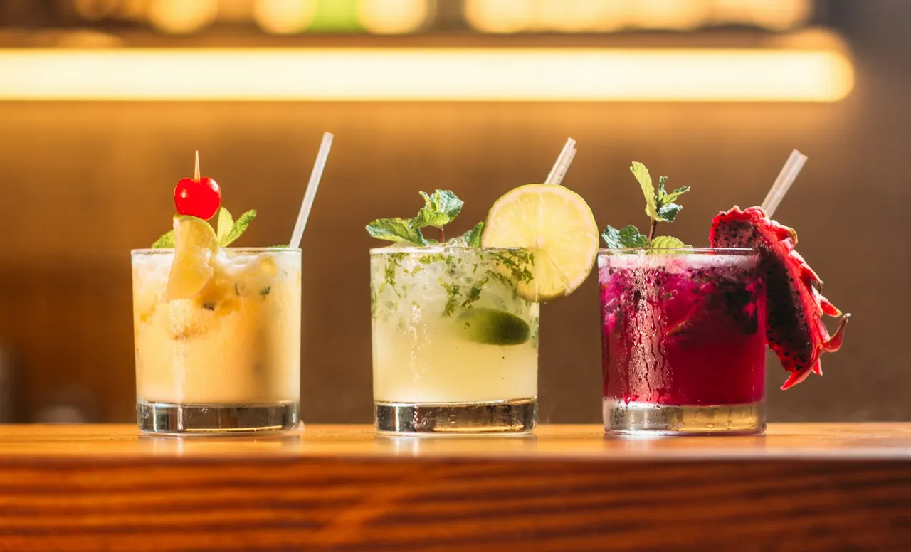 Three bright cocktails lined up on the bar