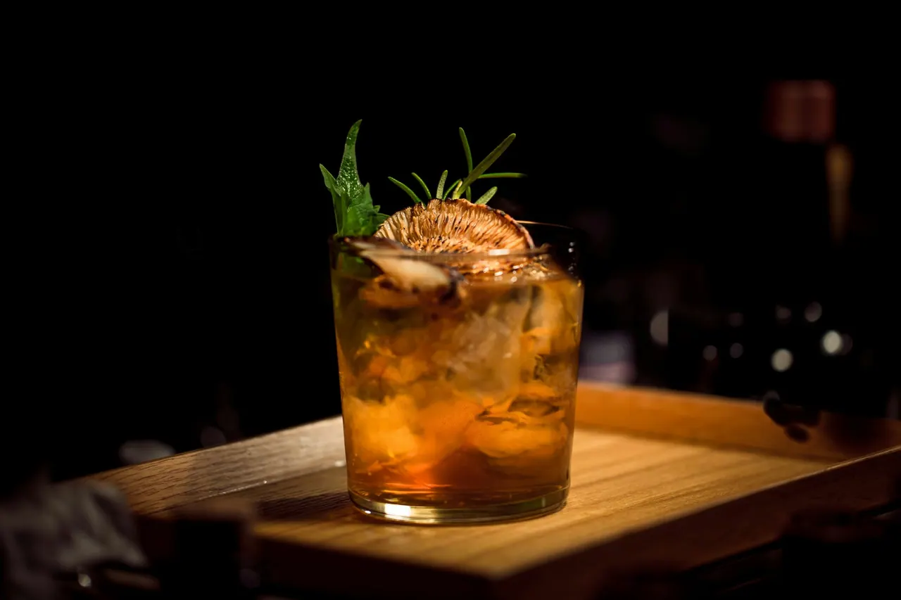 A herb garnished cocktail on a wooden board