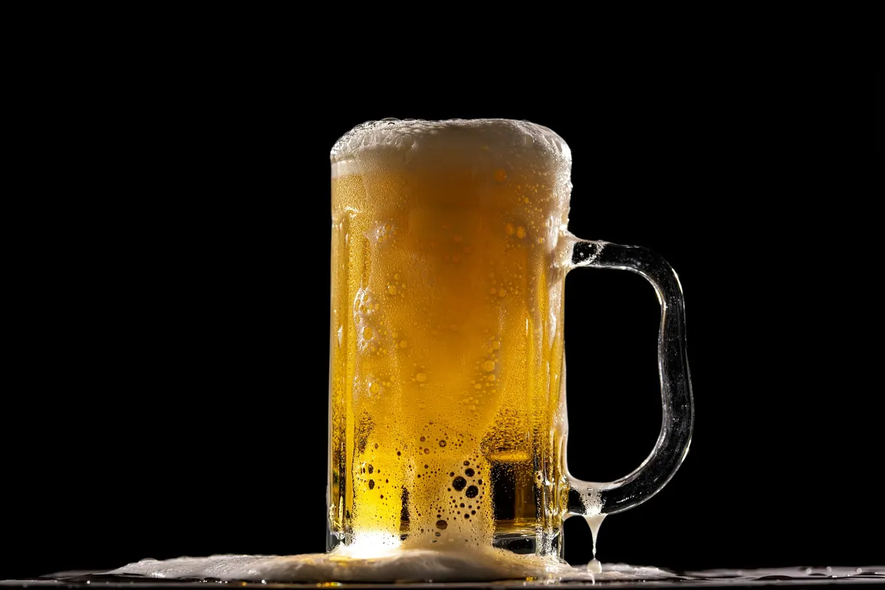 A frothy mug of beer on a black background