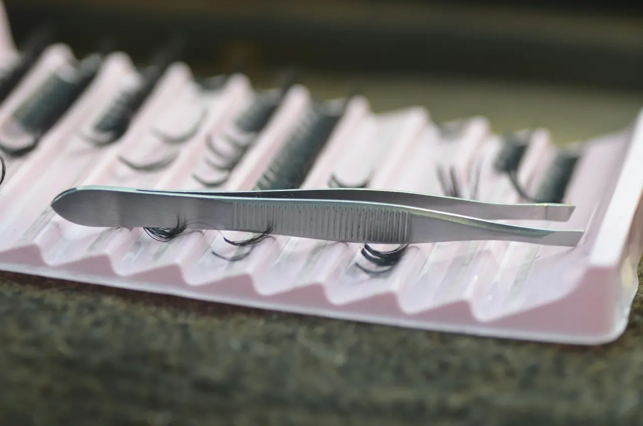 Fine tweezers resting on a tray of lash extensions