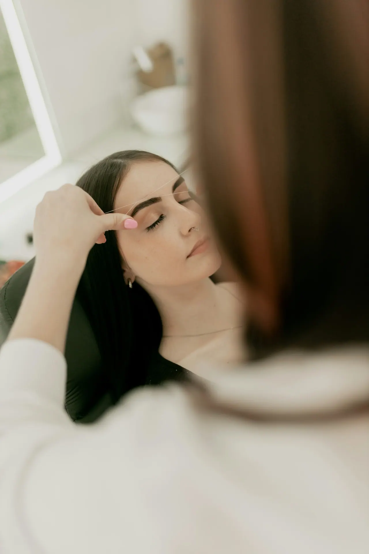 A client resting with her eyes closed during a brow treatment