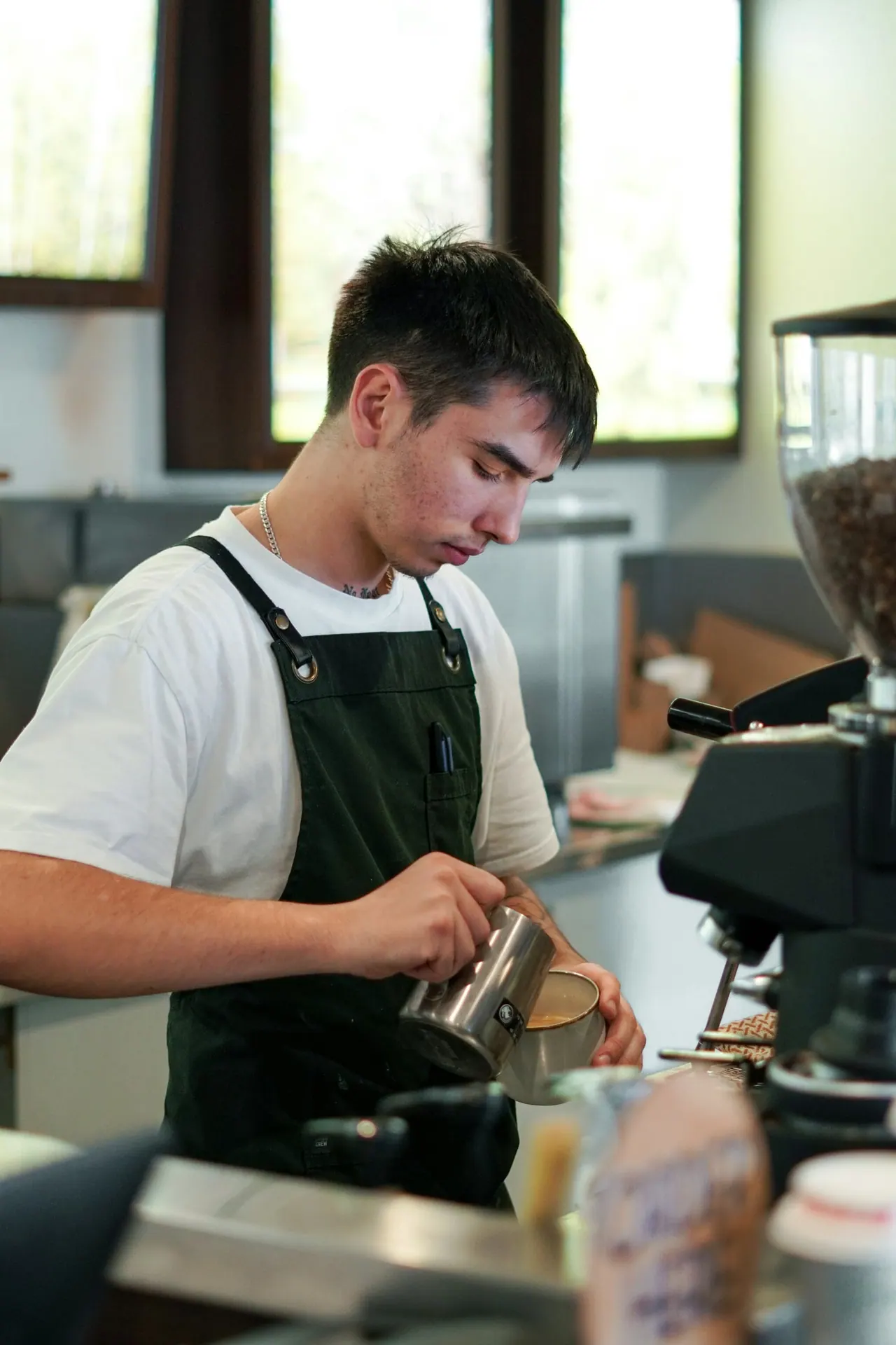 A barista pouring steamed milk into a latte