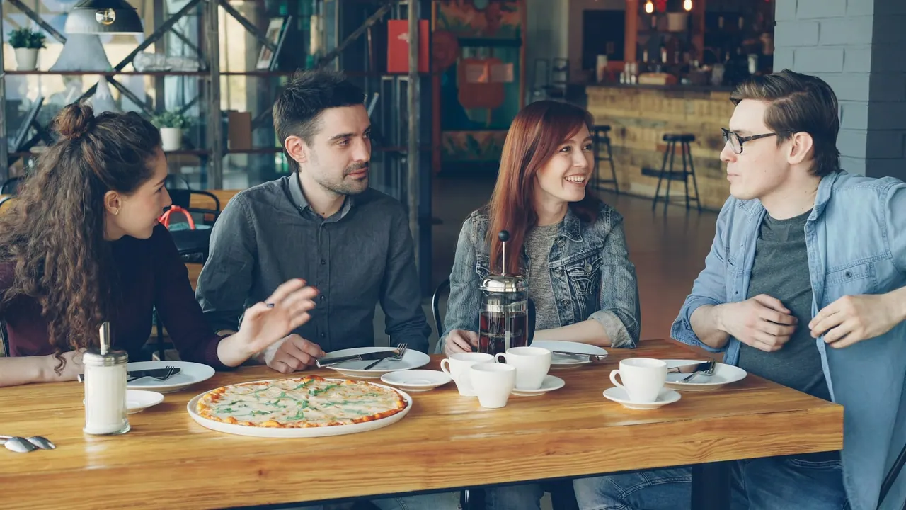 Friends laughing over lunch and coffee at a long table