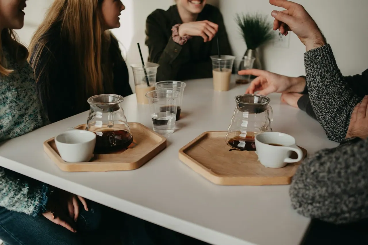 Friends around a cafe table with pour over coffee and iced lattes