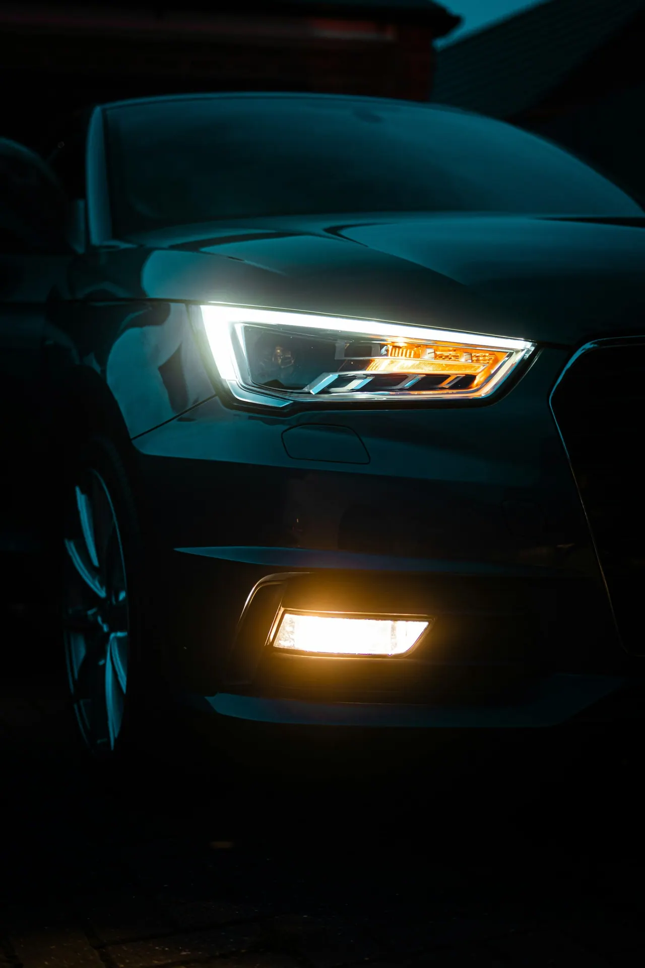 A car's headlight and fog light glowing at night