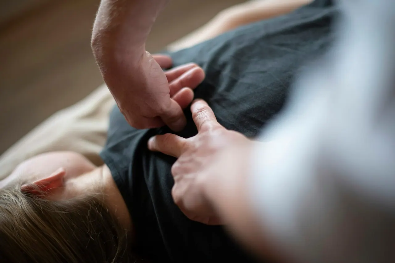 Hands pressing gently into a patient's upper back