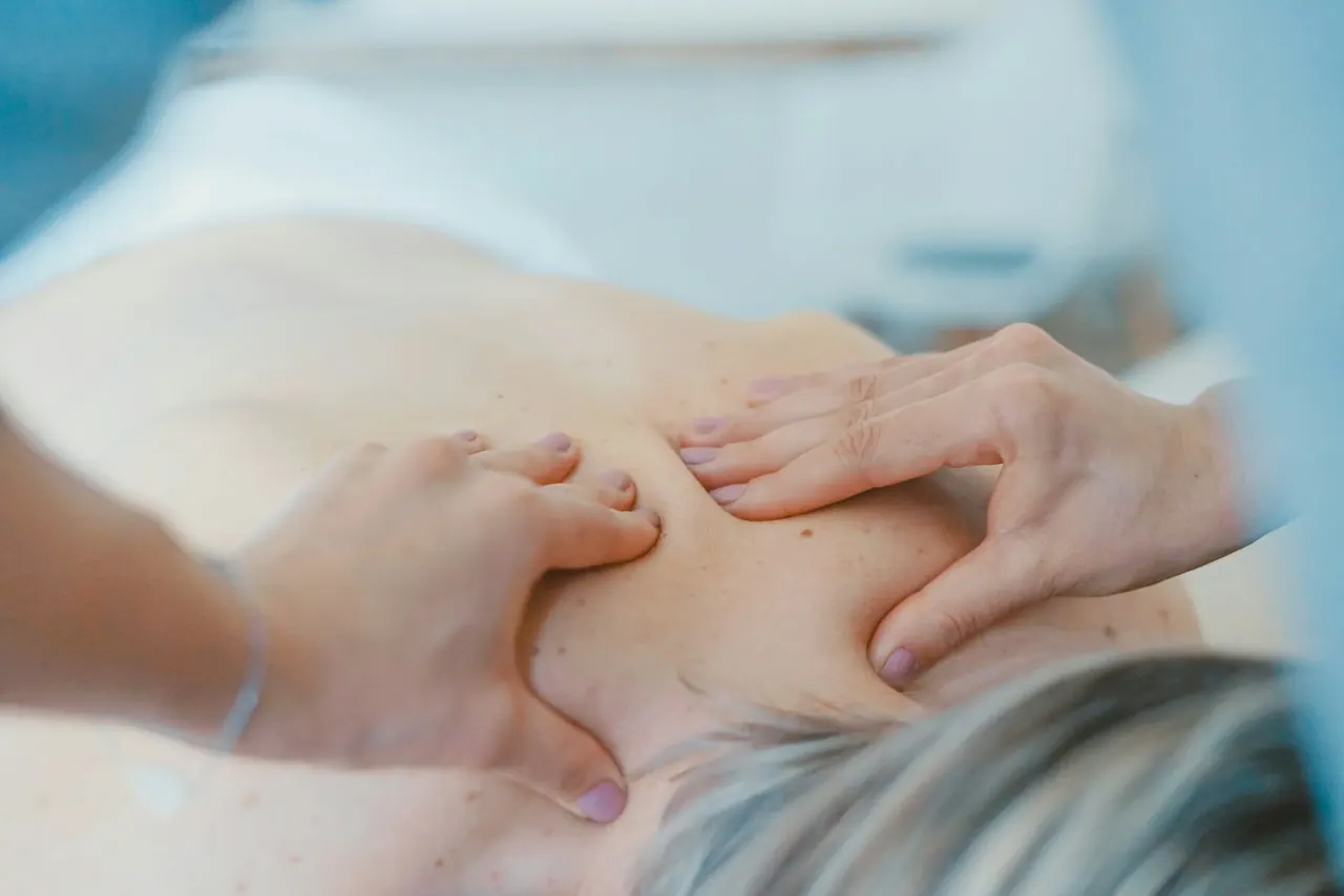 A chiropractor's hands working on a patient's shoulder