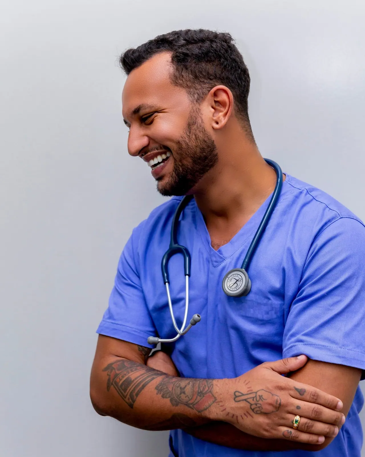A smiling clinician in blue scrubs with a stethoscope