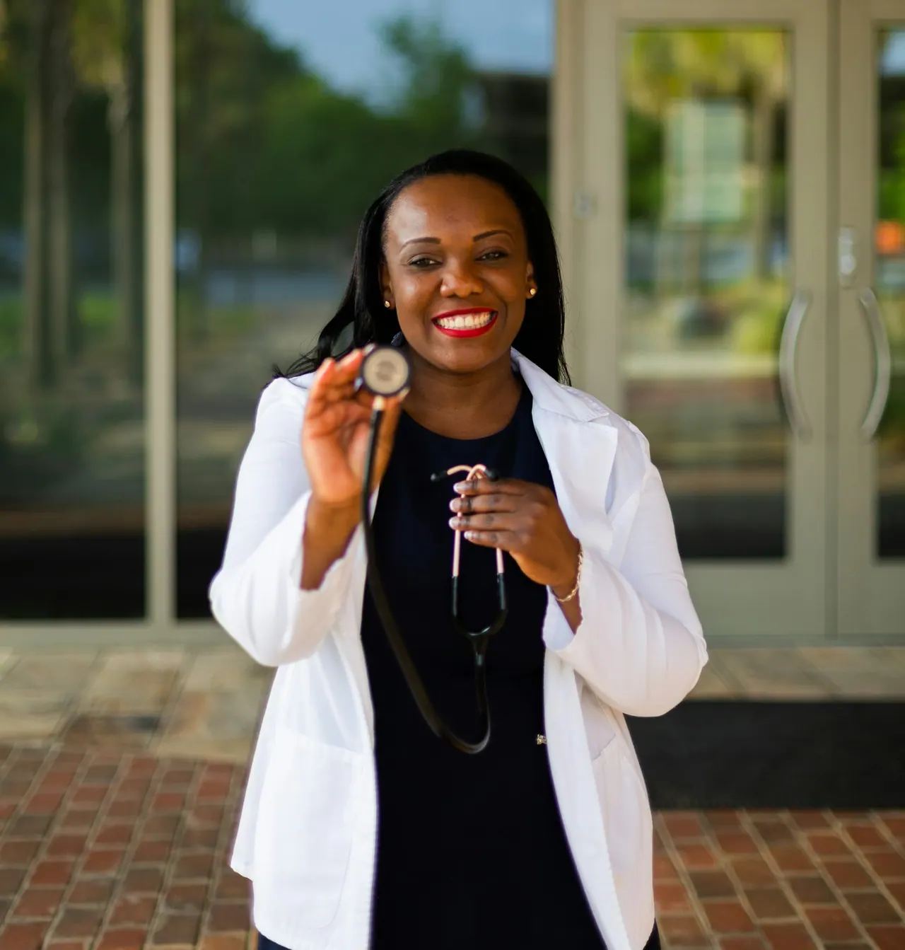 A smiling doctor in a white coat holding a stethoscope