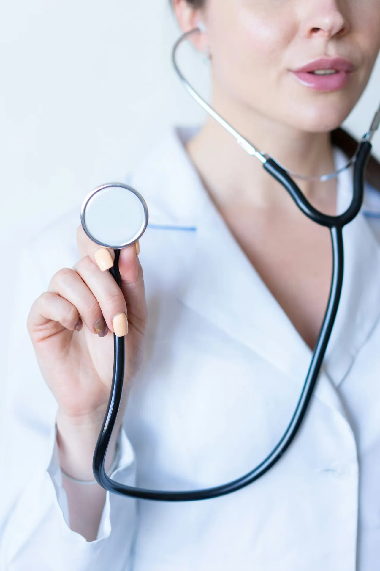 A physician in a white coat holding a stethoscope