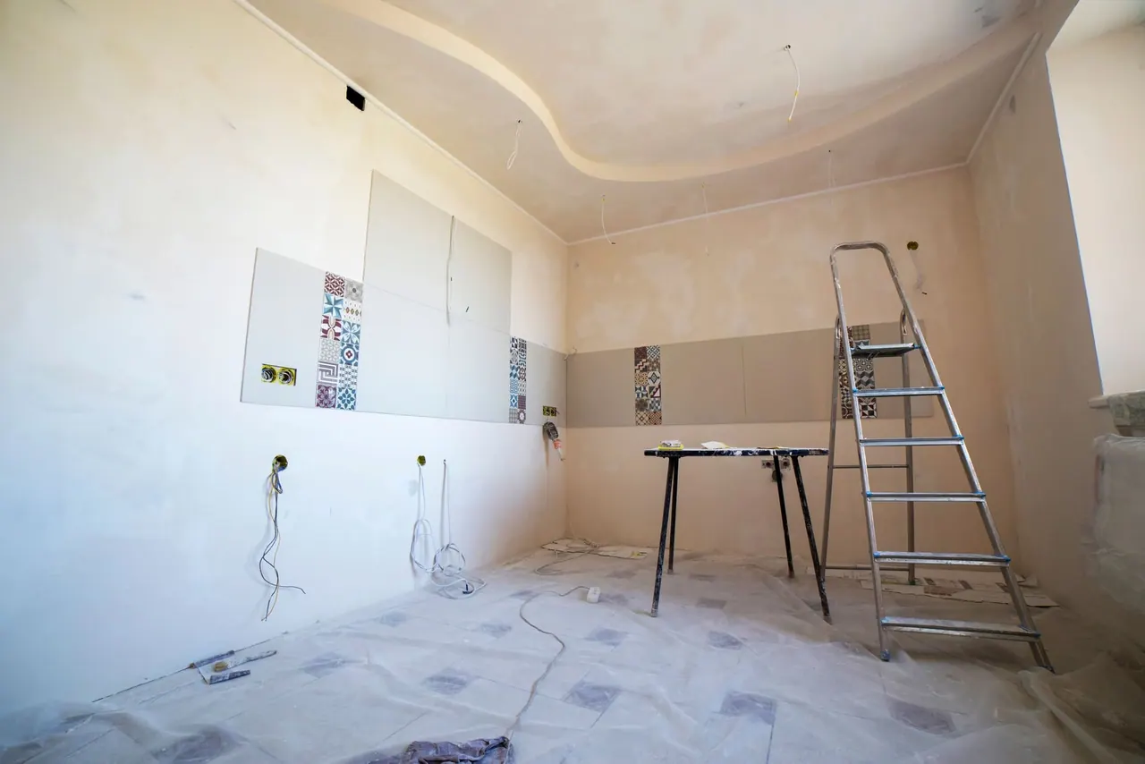 Before: a bare room with ladders, patched walls and a dusty floor