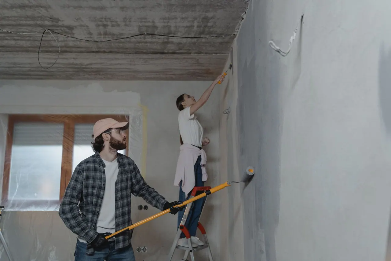 Two of our team repainting a room, one on a ladder