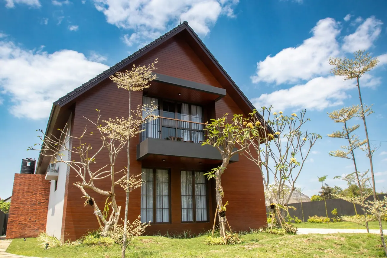 A gabled brick house with a balcony under a bright sky