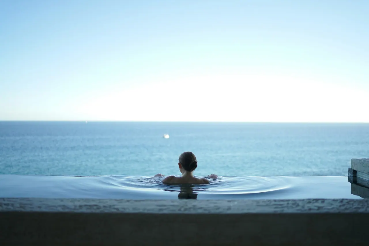 A guest in an infinity pool looking out over calm water