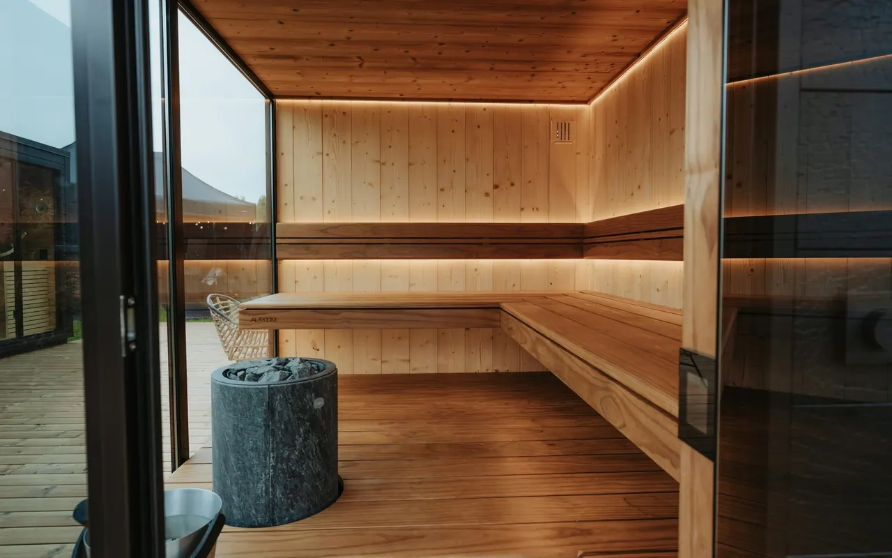 A bright modern sauna with glass walls and warm wood benches
