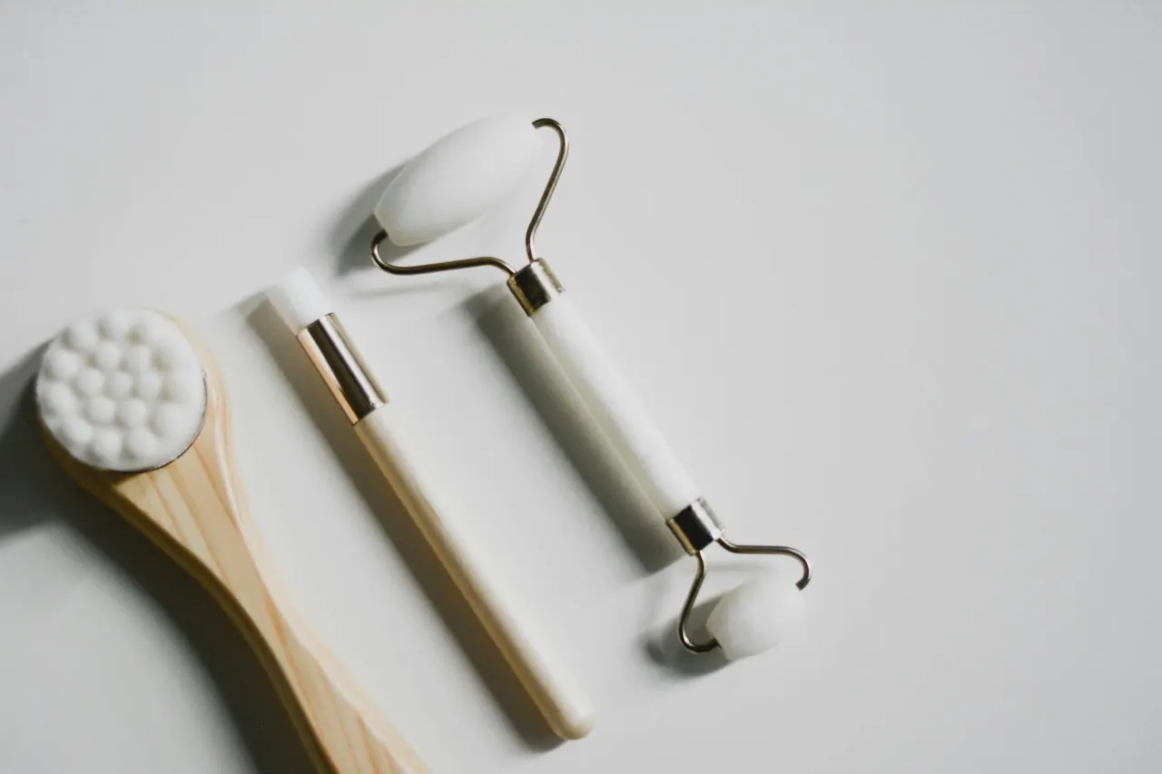 A facial roller and soft brushes on white