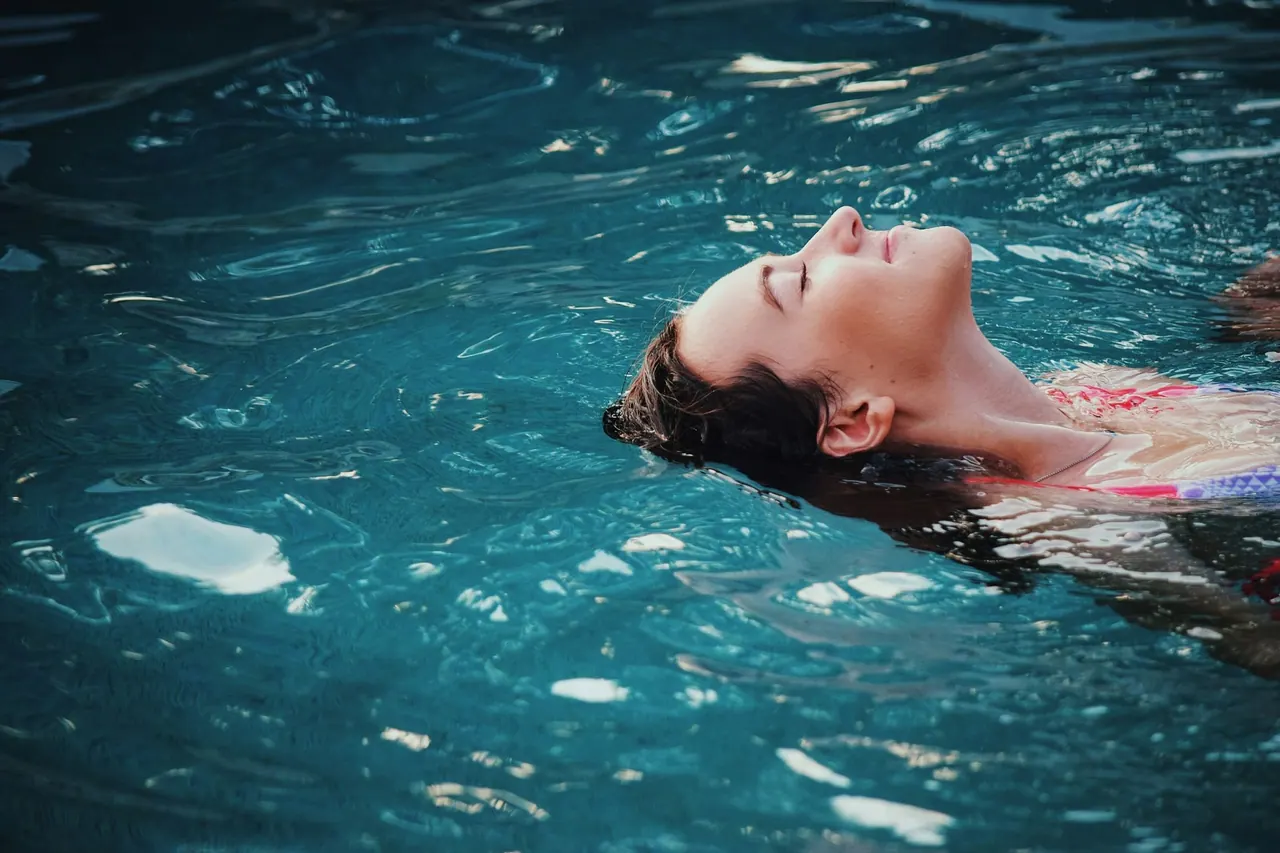 A guest floating on her back in a turquoise pool, eyes closed