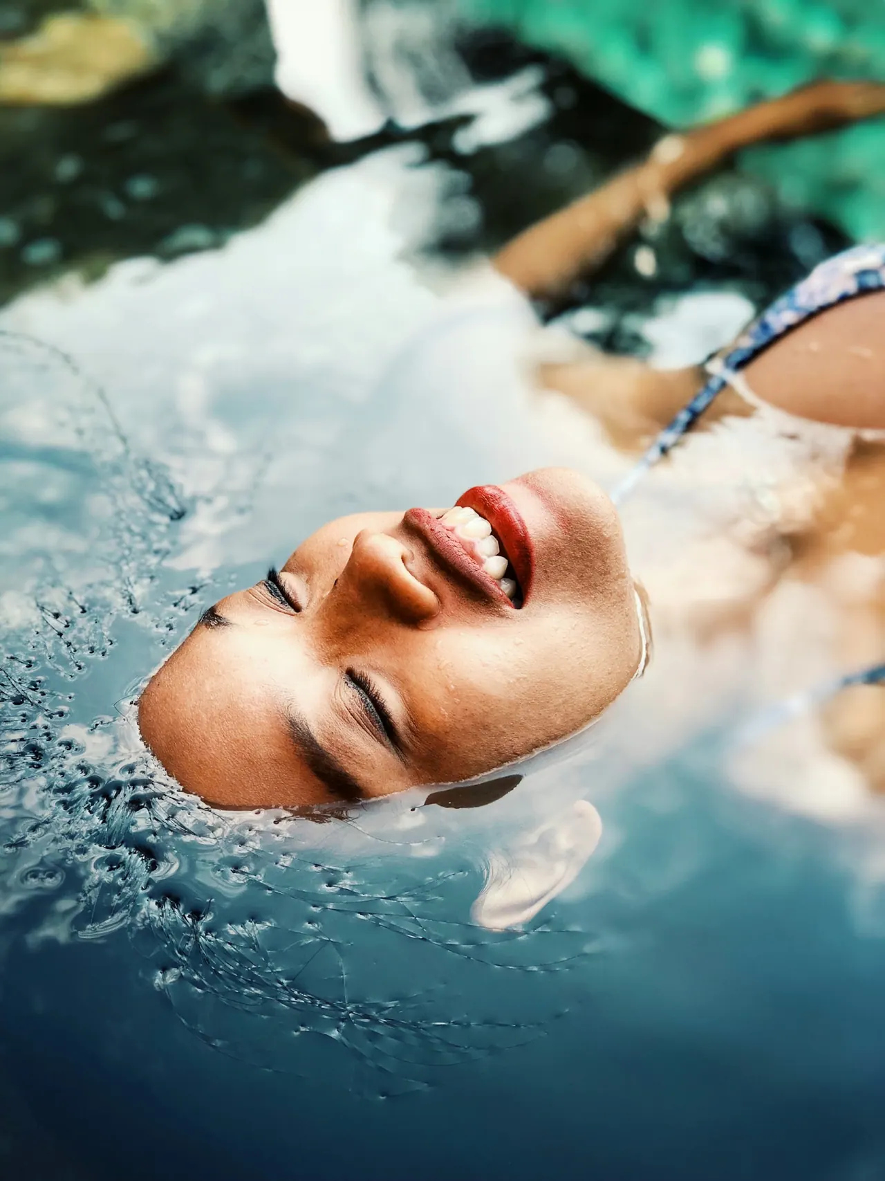 A smiling guest floating on her back in clear, sunlit water