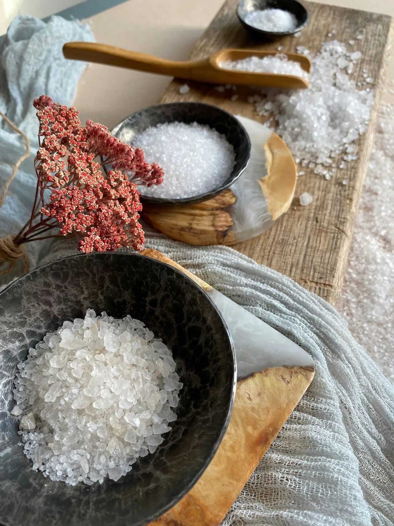 Bowls of bath salt and dried pink flowers on a linen cloth