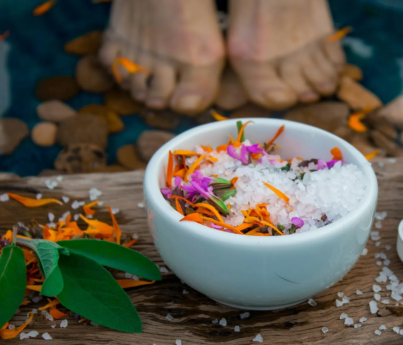 Feet resting beside a bowl of salt and flower petals