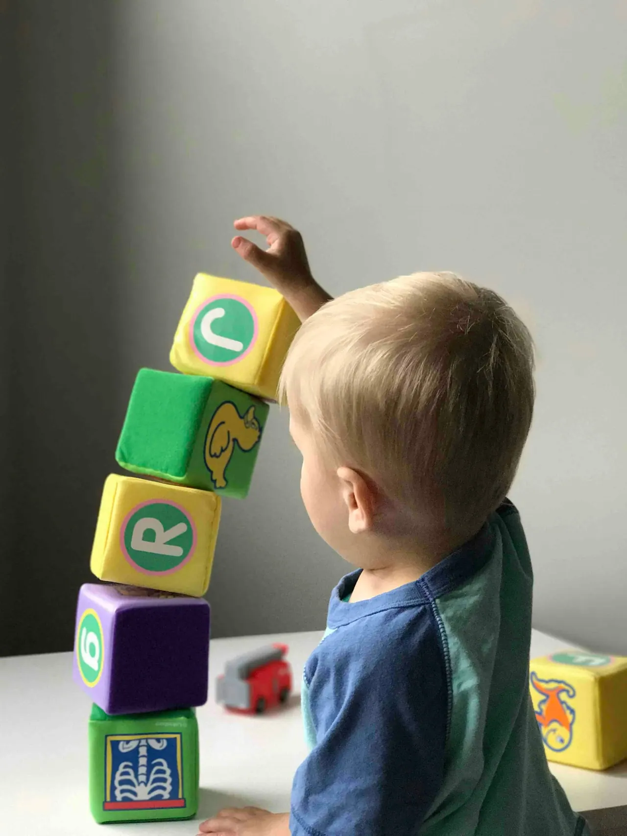 A boy stacking soft letter blocks into a tower