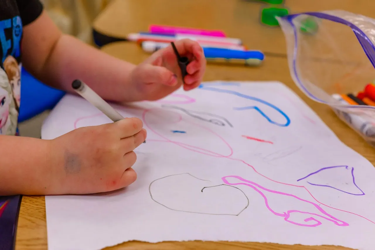 A child drawing loops with coloured markers