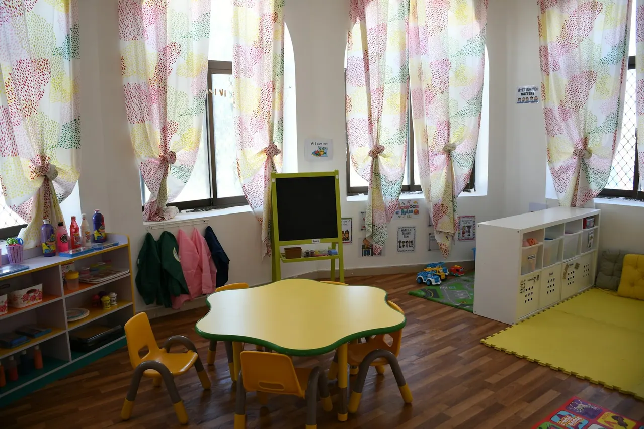 A classroom with a flower shaped table and an easel