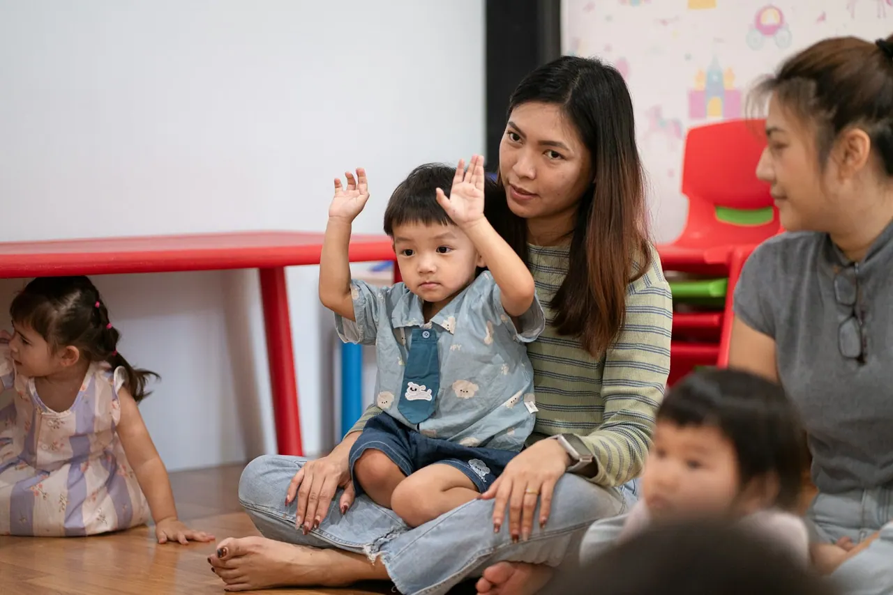A teacher sitting on the floor with a group of toddlers