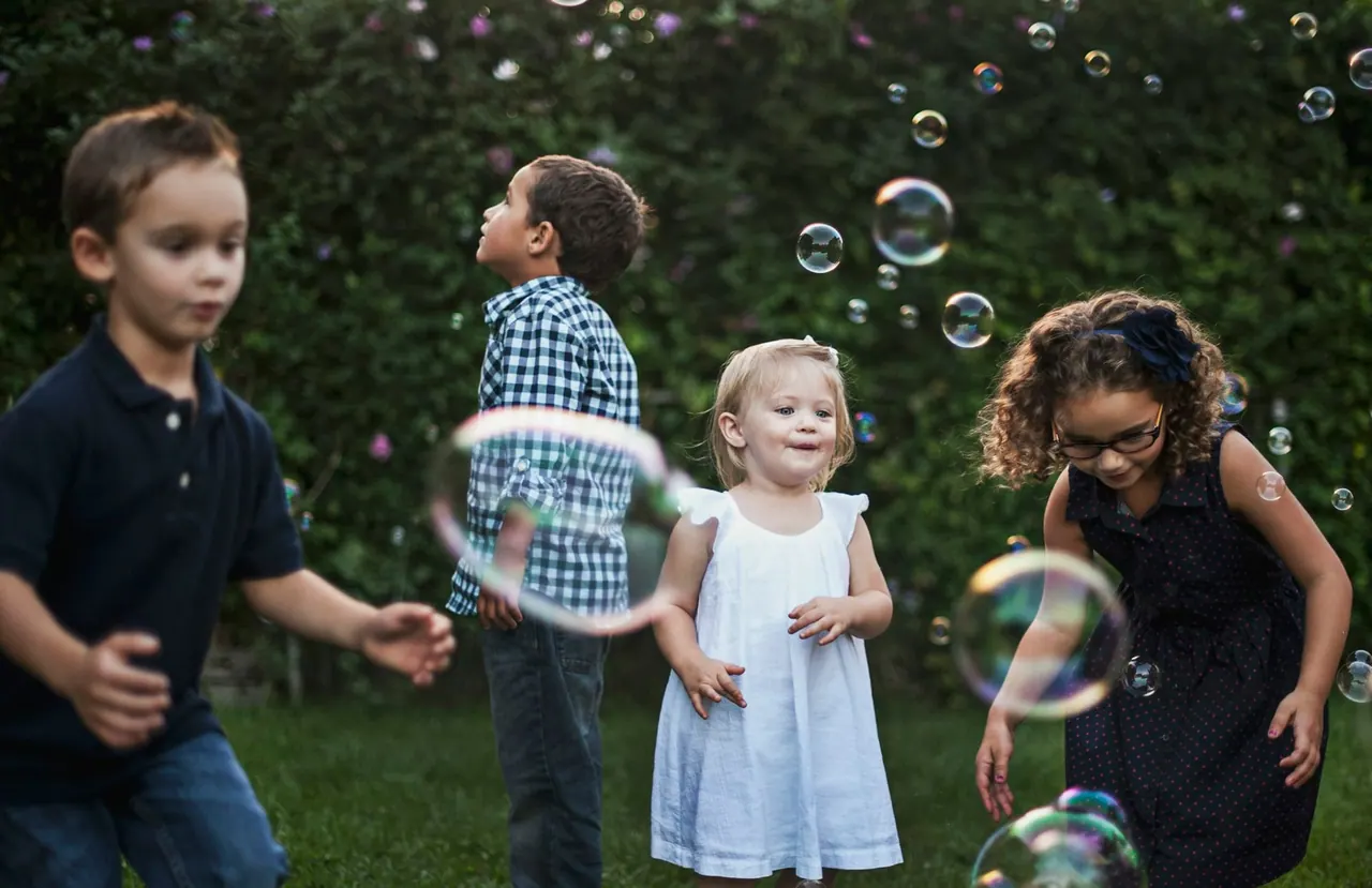 Children playing with soap bubbles on the grass