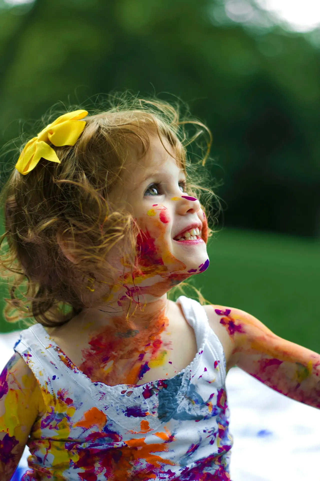 A laughing girl with paint on her face, outdoors