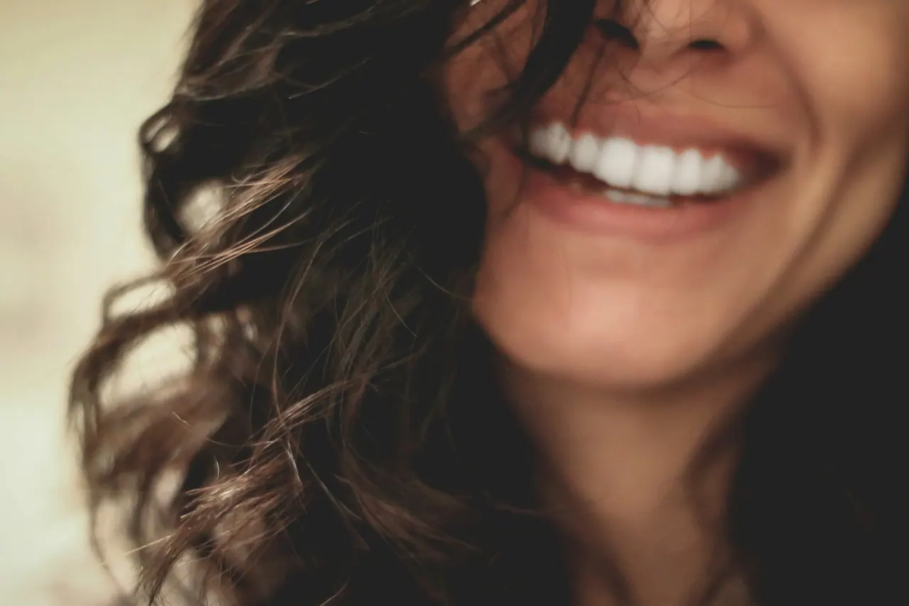 A woman with long dark hair smiling, seen close up
