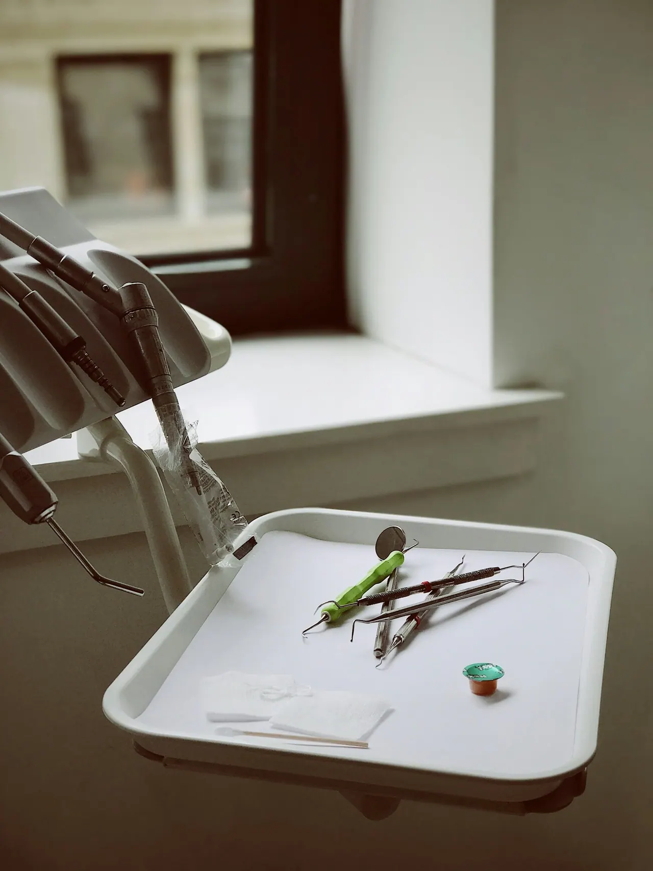 Dental instruments laid out on a white tray by a window