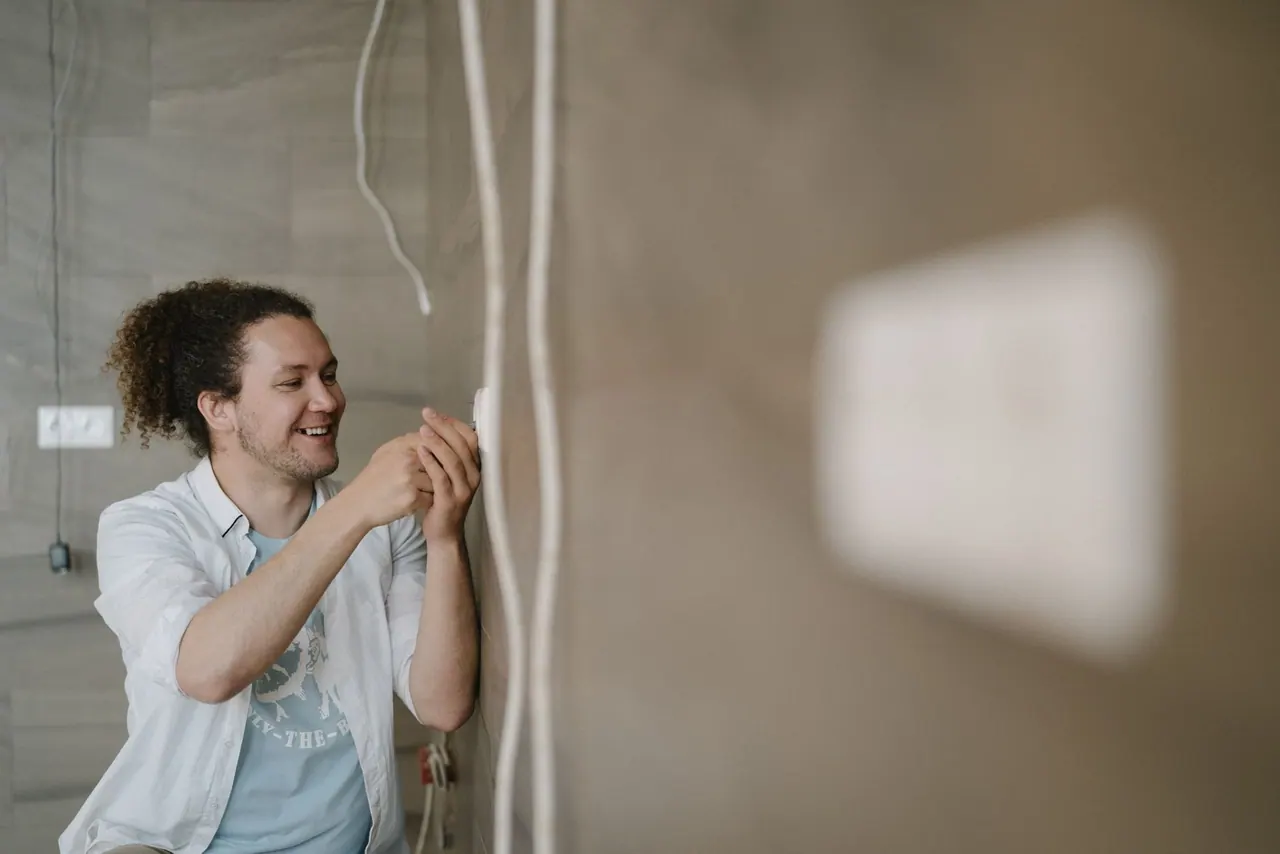 A smiling electrician fitting a new wall outlet