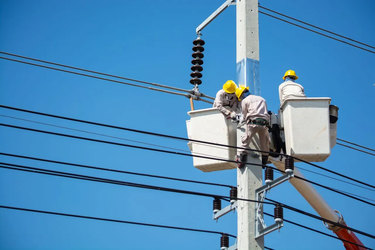 Line workers upgrading overhead power lines from a bucket lift