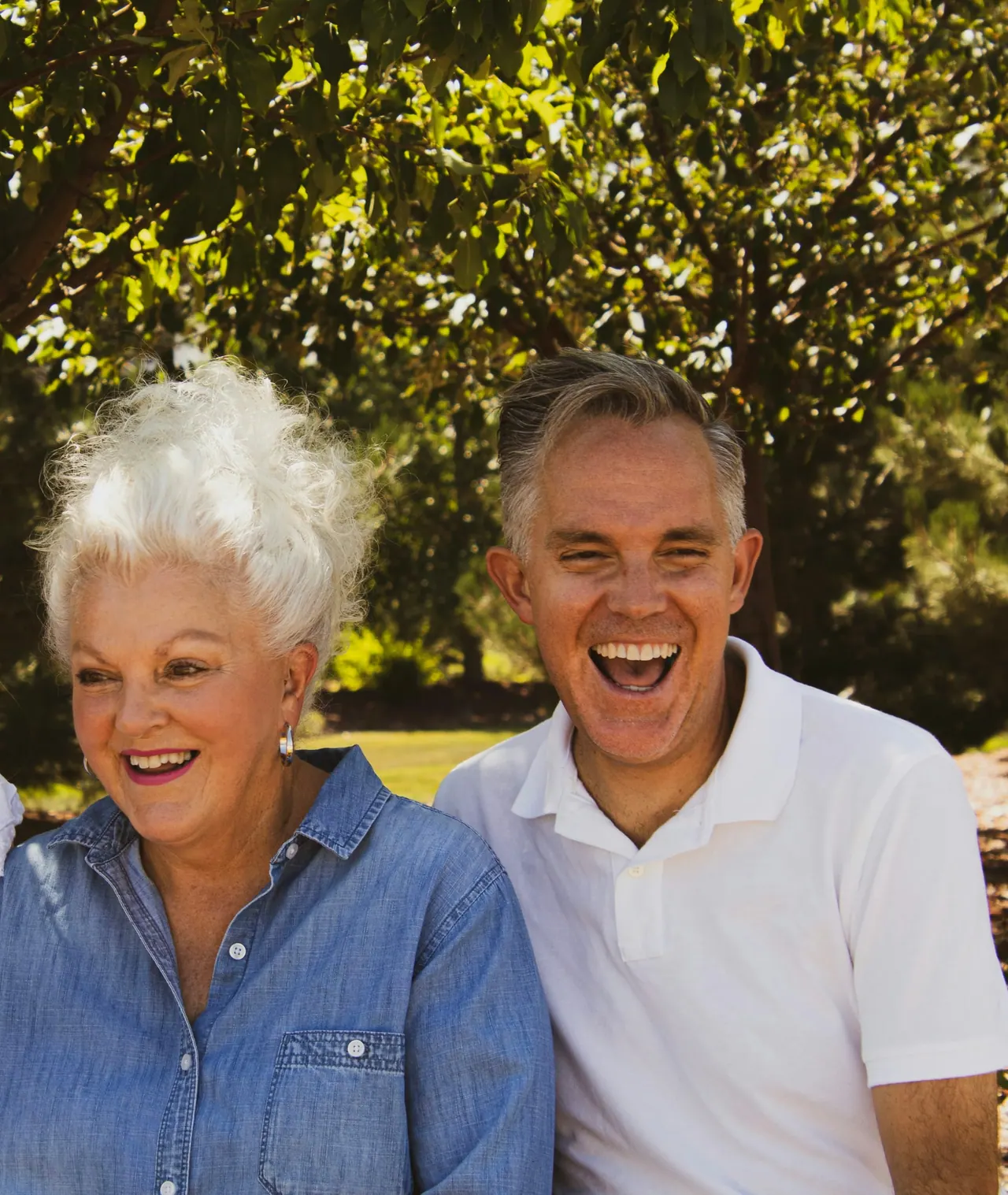 An older couple laughing together under a tree