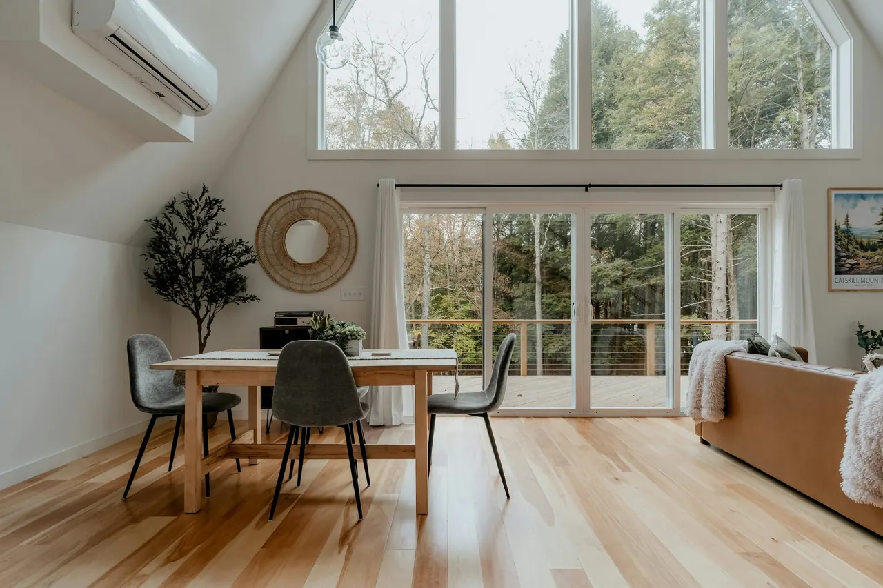 A dining area on pale wood floors with a forest view