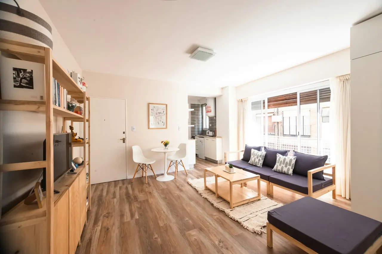 A sunny living room with a navy sofa on mid brown wood floors